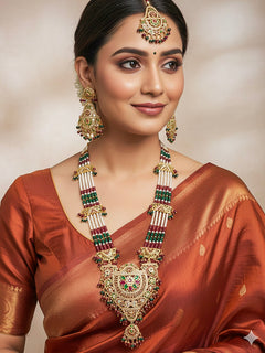 Close-up of a woman wearing an ornate traditional Long jadau gold jewellery set and jadau earrings and maangtikka with crystals beads and gemstones. Perfect Jadau necklace set for weddings and festivals.