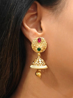Close-up of a woman wearing an ornate traditional (Gold Polish) Earrings set with Colored Stone. Saree look completed with an elegant Colored Stone artificial jewelry piece. Woman wearing trending Colored Stone artificial jewelry for wedding season in India.