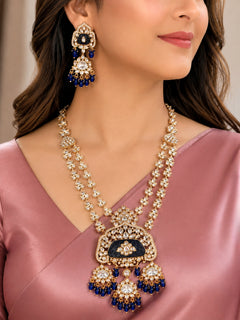 Close-up of a woman wearing an ornate traditional (Gold Polish) Long jewellery set and earrings with Polki, Colored Stones and Tumble Beads. Woman wearing trending Polki artificial jewelry for the wedding season in India. Festive celebration look completed with premium imitation Polki jewelry.