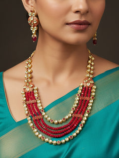 Close-up of a woman wearing an ornate traditional (Gold Polish) Red Kundan jewellery set and earrings with Kundan, Colored Stones, Meenakari and Crystal Beads. Mehendi ceremony look completed with a handcrafted Kundan jewelry set. Close-up of detailed Kundan stones in artificial wedding jewelry.