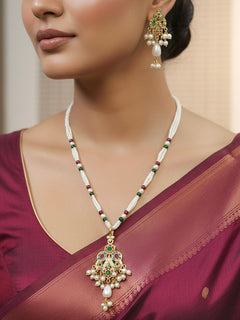 Close-up of a woman wearing an ornate traditional (Gold Polish) Multi-Color Pendant Set and Earrings with Pearl and Colored Stones. Festive saree look completed with a handcrafted Jadau Pendant. Close-up of high-quality Jadau artificial Pendant craftsmanship.