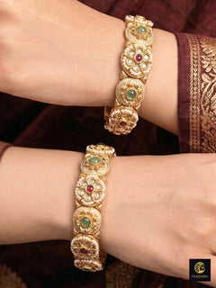 Close-up of a woman wearing an ornate traditional Rajwadi gold Bangle with Red & Mint Green Colored Stone, Bandhai Work and Meenakari. Woman stacking artificial Rajwadi bangles for a festive Diwali celebration. Saree look enhanced with Rajwadi artificial bangles. Festive Diwali outfit paired with a colorful Meenakari Bangles.