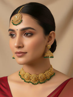 Close-up of a woman wearing an ornate traditional (Gold Polish) Choker jewellery set and earrings and maangtikka with Green Crystal Beads. Woman wearing a luxury artificial jewelry set styled for an Indian wedding celebration. Wedding celebration styling with a luxury artificial jewelry design.