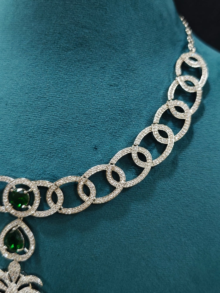 Close-up of an ornate Western (Silver Polish) Collar jewellery set and earrings with American Diamond and Green Colored Stones. Party wear outfit completed with a lightweight American diamond necklace. Model wearing a lightweight American diamond necklace perfect for long wedding functions.
Close-up of a bridal look featuring an anti-tarnish American diamond artificial necklace.