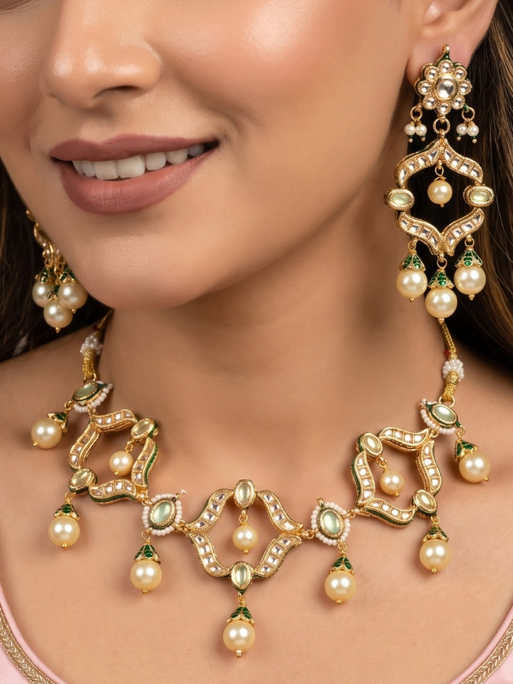 Woman wearing a green Kundan necklace set with cream pearl drops and long chandelier earrings