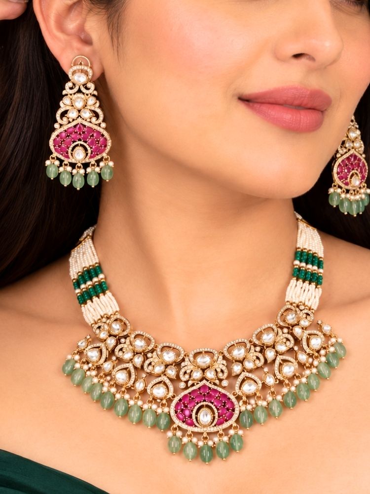 Rosabel Necklace Set – woman wearing a polki choker with pearl and green bead strands and a ruby pink fan pendant and matching earrings, styled with a green outfit, artificial jewellery for weddings and sangeet