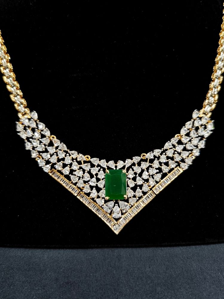 Close-up of an ornate Western (Silver Polish) Green Collar jewellery set and earrings with Green Colored Stone and American Diamond. Woman styling a statement American diamond necklace with an off-shoulder gown for a reception. Party wear outfit completed with a lightweight American diamond necklace.