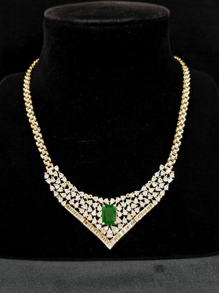 Close-up of an ornate Western (Silver Polish) Green Collar jewellery set and earrings with Green Colored Stone and American Diamond. Woman styling a statement American diamond necklace with an off-shoulder gown for a reception. Party wear outfit completed with a lightweight American diamond necklace.