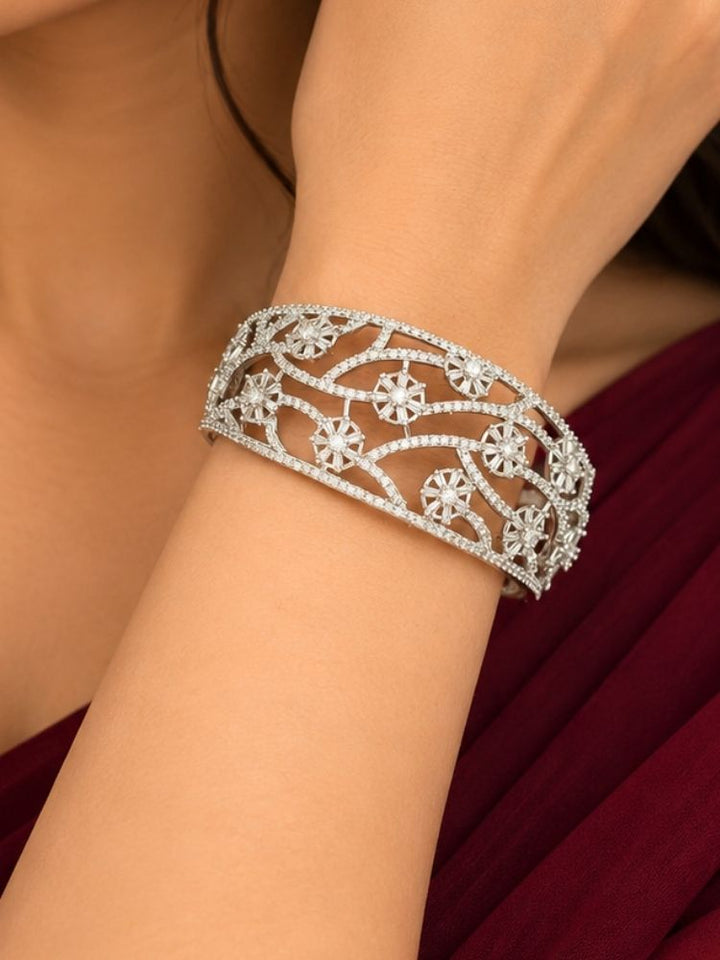 Woman wearing the Colombine Silver Floral Zirconia Bracelet – close-up of a broad openable silver bracelet with an American diamond floral vine pattern on the wrist, artificial jewellery for parties and weddings