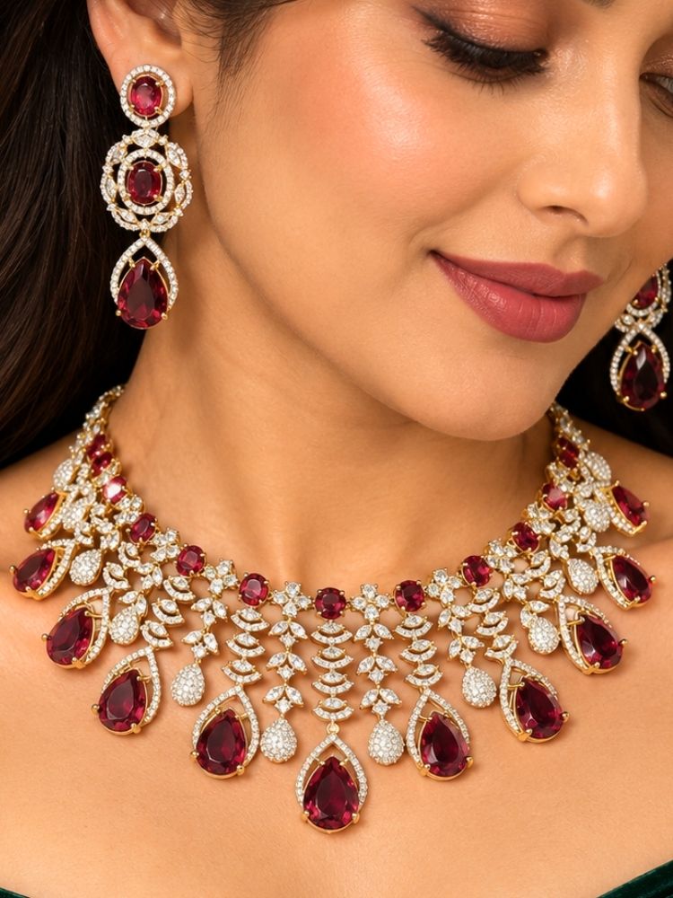 Chantilly Necklace Set – woman wearing a silver-tone American diamond collar necklace with ruby red teardrop stones and matching earrings, styled with a green off-shoulder outfit, artificial jewellery for reception and engagement