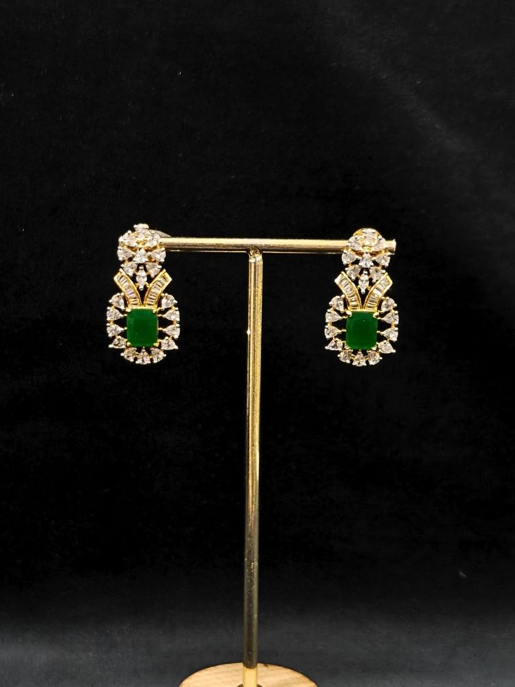 Close-up of an ornate Western (Silver Polish) Green Collar jewellery set and earrings with Green Colored Stone and American Diamond. Woman styling a statement American diamond necklace with an off-shoulder gown for a reception. Party wear outfit completed with a lightweight American diamond necklace.