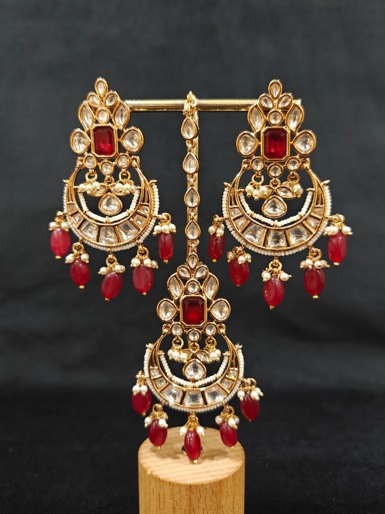 Close-up of an ornate traditional (Gold Polish) Collar jewellery set and earrings and maangtikka with Red Colored Stones, Polki, Kundan, Tumble beads and Pearls. Bride wearing a statement Polki jewelry set for wedding photos. Woman wearing trending Polki artificial jewelry for the wedding season in India.