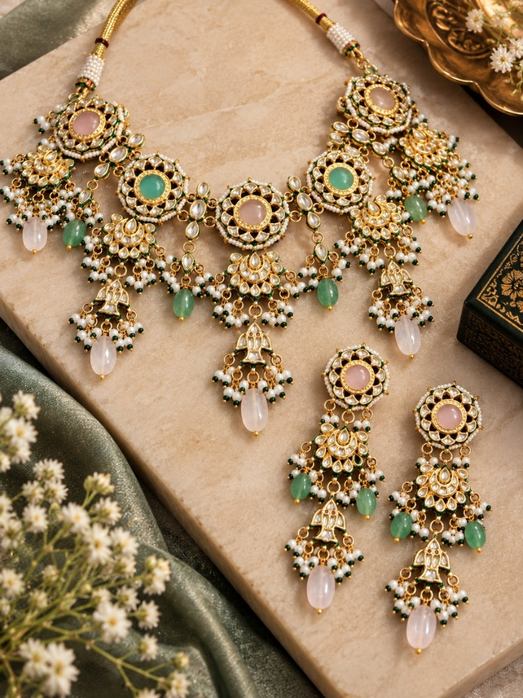 Flat lay of a pastel Kundan choker set with gold kalash charms, pearl fringe and blush drop beads