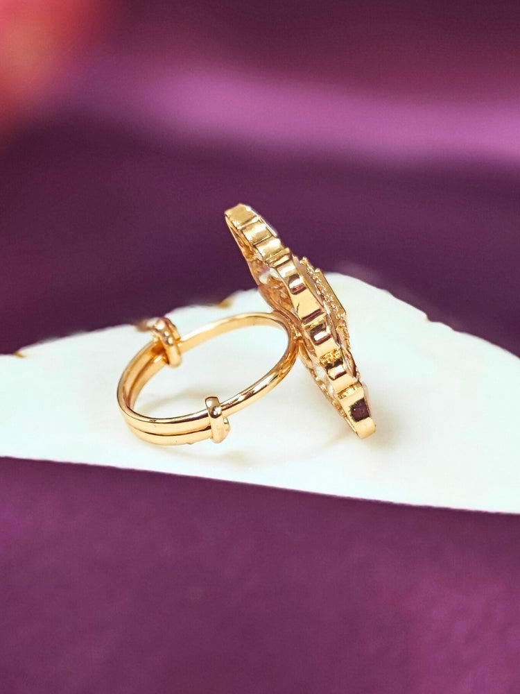 Gold ring with intricate design on a white marble against a purple background
