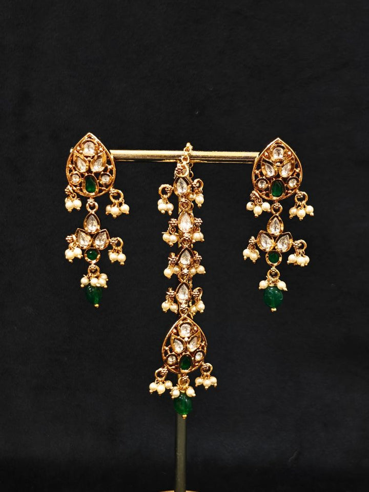 Close-up of an ornate traditional (Gold Polish) Green Collar jewellery set and earrings and maangtikka with Polki, Green Colored Stones, Tumble Beads and Pearls. Woman wearing trending Polki artificial jewelry for the wedding season in India. Woman wearing a lightweight Polki jewelry set for long wedding functions.