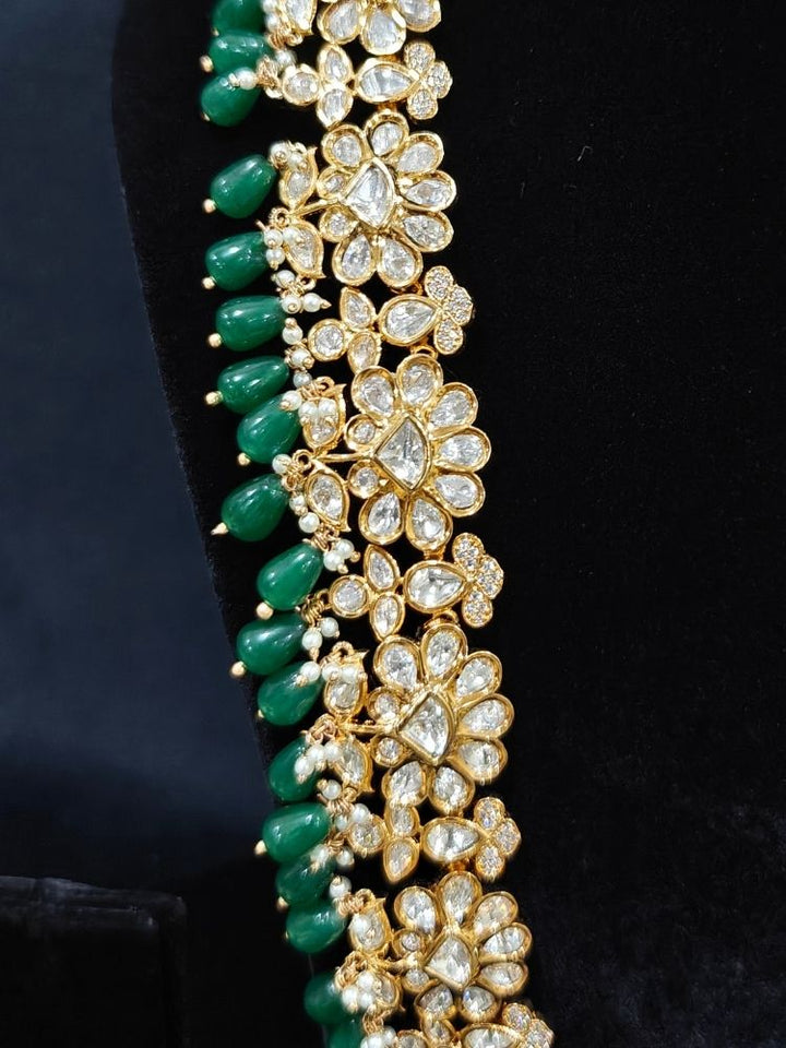 Close-up of an ornate traditional (Gold Polish) Long jewellery set and earrings with Polki, American Diamond Tumble Beads and Pearls. Wedding guest outfit styled with an elegant Polki necklace set. Woman Bridal mehendi outfit paired with a royal Polki artificial jewelry set. wearing trending Polki artificial jewelry for the wedding season in India. 