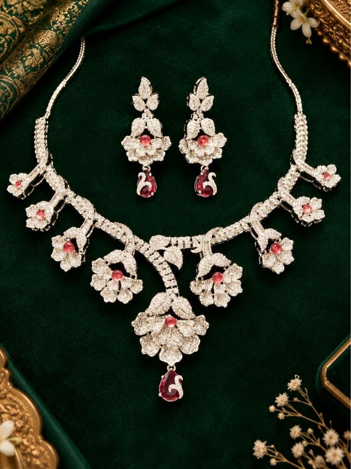 Oleander American Diamond Red Silver Tone Necklace Set with earrings on fabric – a silver-tone American diamond floral necklace with ruby red drops, traditional jewellery set for women