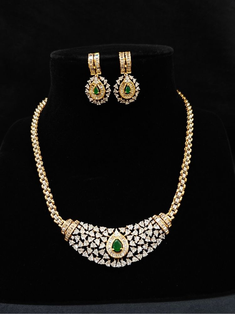 Close-up of an ornate Western (Silver Polish) Green Collar jewellery set and earrings with Green Colored Stone and American Diamond.Woman styling a statement American diamond necklace with an off-shoulder gown for a reception. Party wear outfit completed with a lightweight American diamond necklace.