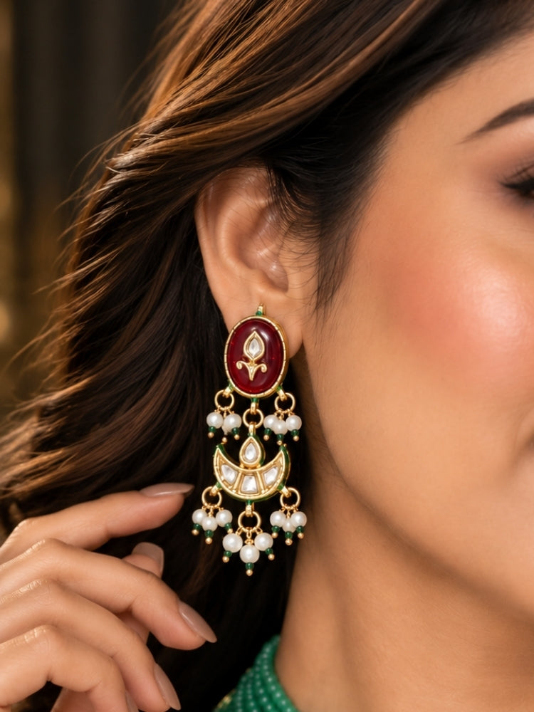 Close-up of a maroon Kundan earring with gold crescent motif and white pearl fringe