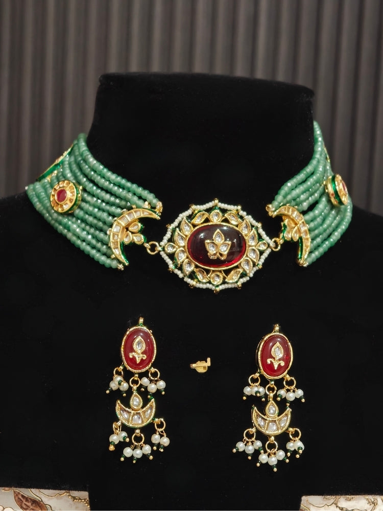 Green bead choker and matching Kundan earrings with maroon stones on a display bust