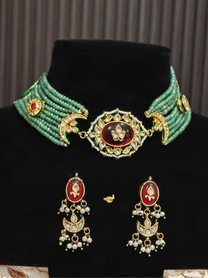 Green bead choker and matching Kundan earrings with maroon stones on a display bust