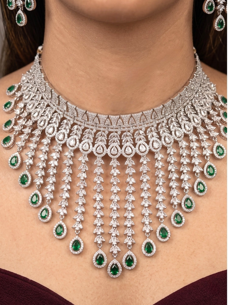 Close-up of a woman wearing an ornate Western (Silver Polish) Diamond Green Choker jewellery set and earrings with American Diamond and Green Colored Stones. Woman styling a statement American diamond necklace with an off-shoulder gown for a reception. A graceful woman wearing a trending American diamond necklace for a 2026 wedding celebration.