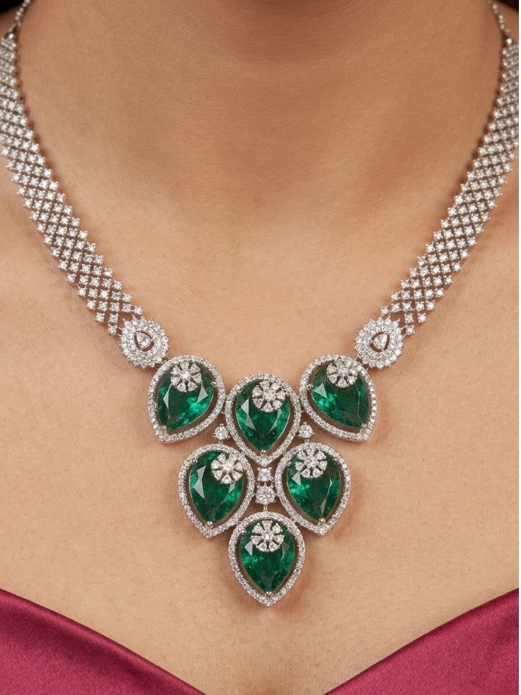Close-up of a woman wearing an ornate Western (Silver Polish) Diamond Green Collar jewellery set and earrings with American Diamond and Green Colored Stones. Close-up shot of a high-quality American diamond artificial necklace worn for festive celebrations. Party wear outfit completed with a lightweight American diamond necklace.