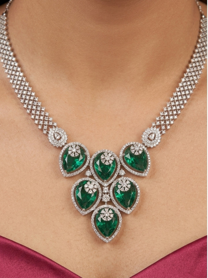 Close-up of a woman wearing an ornate Western (Silver Polish) Diamond Green Collar jewellery set and earrings with American Diamond and Green Colored Stones. Close-up shot of a high-quality American diamond artificial necklace worn for festive celebrations. Party wear outfit completed with a lightweight American diamond necklace.