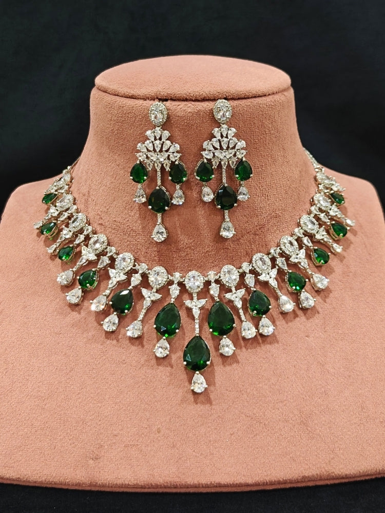 Close-up of an ornate Western (Silver Polish) Diamond Green Collar jewellery set and earrings with American Diamond and Green Colored Stone. Party wear outfit completed with a lightweight American diamond necklace. Elegant wedding jewelry look featuring a premium artificial American diamond necklace.