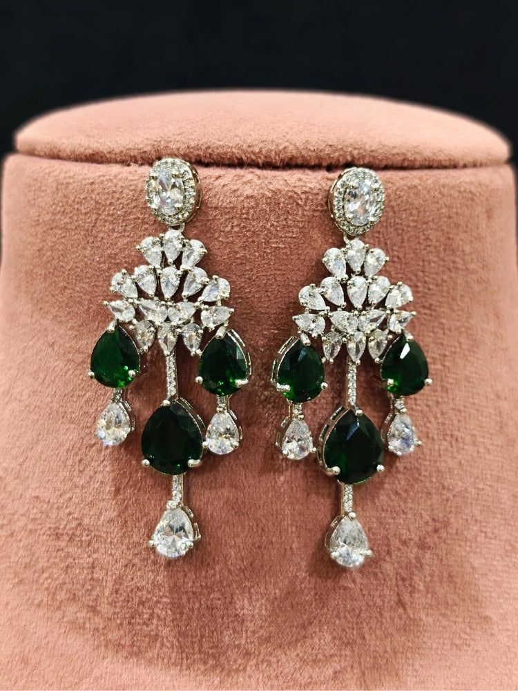 Close-up of an ornate Western (Silver Polish) Diamond Green Collar jewellery set and earrings with American Diamond and Green Colored Stone. Party wear outfit completed with a lightweight American diamond necklace. Elegant wedding jewelry look featuring a premium artificial American diamond necklace.