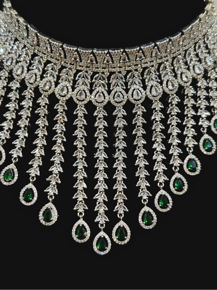 Close-up of an ornate Western (Silver Polish) Diamond Green Choker jewellery set and earrings with American Diamond and Green Colored Stones. Woman styling a statement American diamond necklace with an off-shoulder gown for a reception. A graceful woman wearing a trending American diamond necklace for a 2026 wedding celebration.