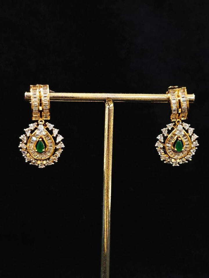 Close-up of an ornate Western (Silver Polish) Green Collar jewellery set and earrings with Green Colored Stone and American Diamond.Woman styling a statement American diamond necklace with an off-shoulder gown for a reception. Party wear outfit completed with a lightweight American diamond necklace.
