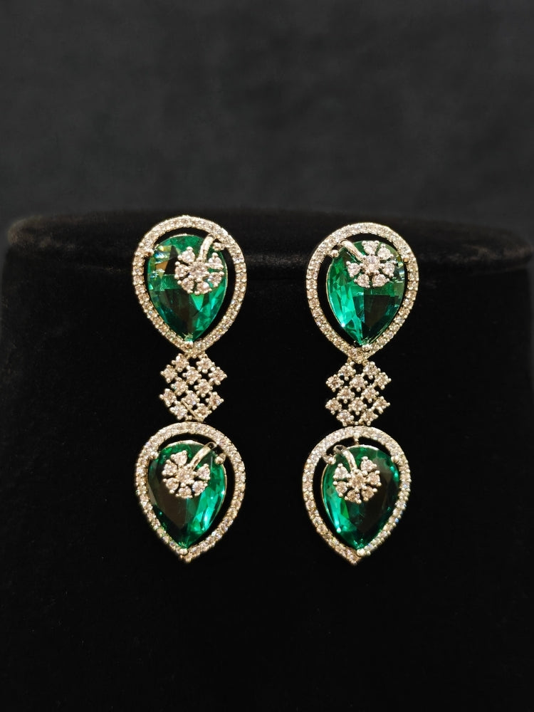 Close-up of an ornate Western (Silver Polish) Diamond Green Collar jewellery set and earrings with American Diamond and Green Colored Stones. Close-up shot of a high-quality American diamond artificial necklace worn for festive celebrations. Party wear outfit completed with a lightweight American diamond necklace.