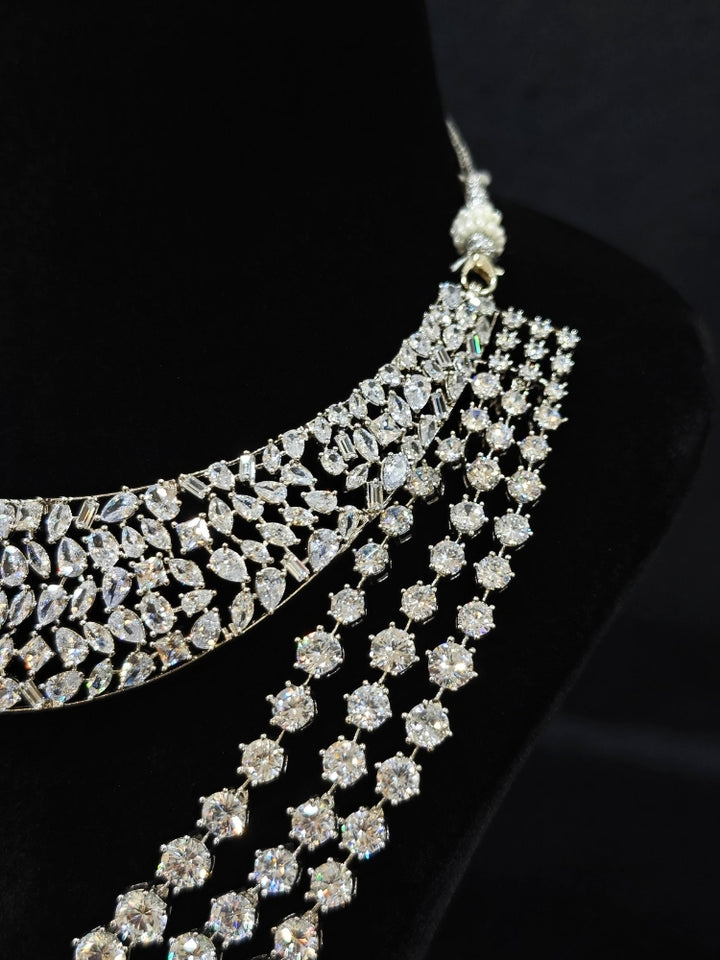 Close-up of an ornate Western (Silver Polish) Layered jewellery set and earrings with American Diamond and Champaign Colored Stones. Elegant wedding jewelry look featuring a premium artificial American diamond necklace. A graceful woman wearing a trending American diamond necklace for a 2026 wedding celebration.