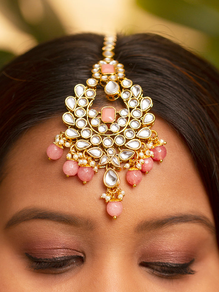 Close-up of a woman wearing an ornate traditional Pink Kundan Choker jewellery set and earrings and maangtikka with Kundan, Mint Pink Stone, Pearls and Mint Pink Crystal Beads. Bride wearing a royal Kundan artificial necklace for wedding rituals. Wedding celebration look enhanced with a statement Kundan necklace. 