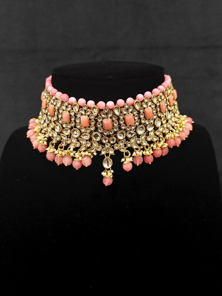 Close-up of an ornate traditional Pink Kundan Choker jewellery set and earrings and maangtikka with Kundan, Mint Pink Stone, Pearls and Mint Pink Crystal Beads. Bride wearing a royal Kundan artificial necklace for wedding rituals. Wedding celebration look enhanced with a statement Kundan necklace. 