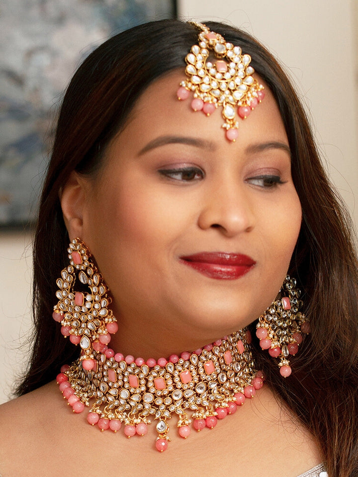 Close-up of a woman wearing an ornate traditional Pink Kundan Choker jewellery set and earrings and maangtikka with Kundan, Mint Pink Stone, Pearls and Mint Pink Crystal Beads. Bride wearing a royal Kundan artificial necklace for wedding rituals. Wedding celebration look enhanced with a statement Kundan necklace. 