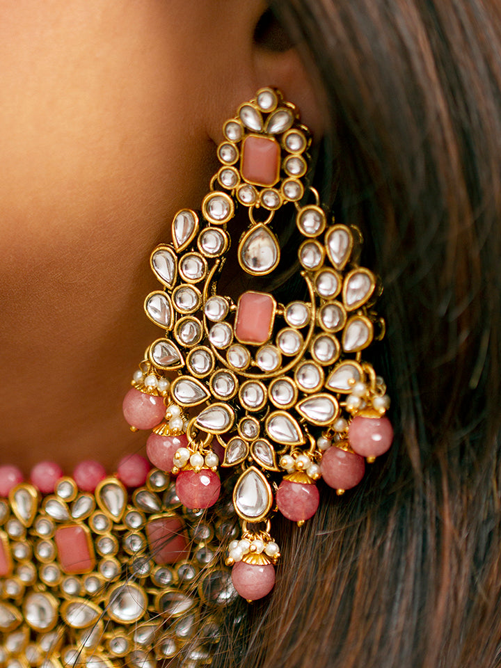 Close-up of a woman wearing an ornate traditional Pink Kundan Choker jewellery set and earrings and maangtikka with Kundan, Mint Pink Stone, Pearls and Mint Pink Crystal Beads. Bride wearing a royal Kundan artificial necklace for wedding rituals. Wedding celebration look enhanced with a statement Kundan necklace. 