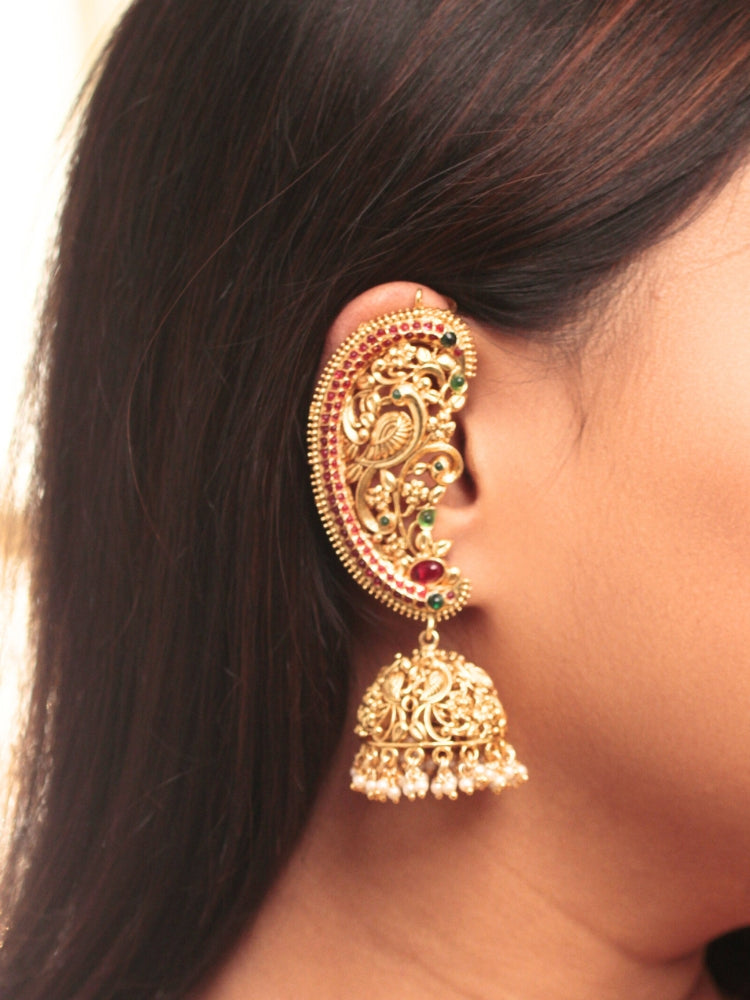 A close-up of a womans ear adorned with Aarzoo Kaanphool Earrings—ornate gold earrings featuring colorful gemstones, intricate designs, and pearl-accented hanging jhumka—ideal as ethnic or wedding jewelry. The earring covers her entire ear giving an exclusive look. 