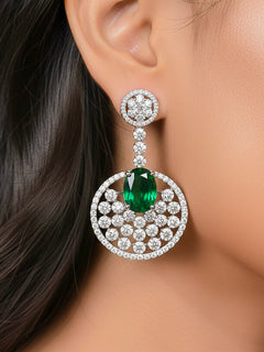 Close-up of a woman wearing an ornate Western (Silver Polish) Green Diamond Earrings with American Diamond and Colored Stones. Bride wearing luxury artificial American Diamond earrings for reception night. Reception-ready look completed with statement artificial jewelry American Diamond earrings.