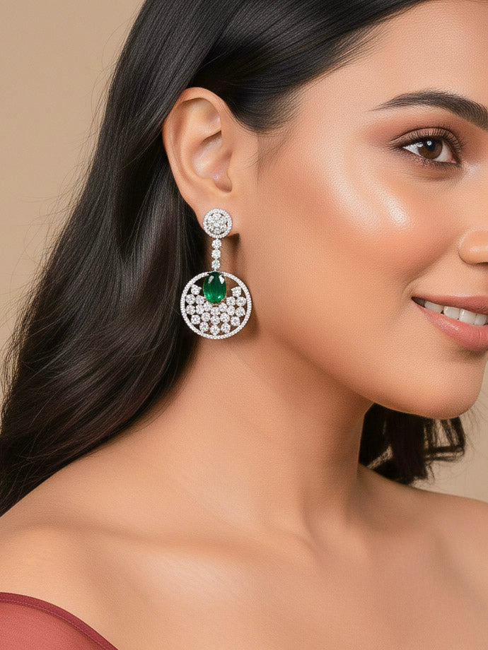 Close-up of a woman wearing an ornate Western (Silver Polish) Green Diamond Earrings with American Diamond and Colored Stones. Bride wearing luxury artificial American Diamond earrings for reception night. Reception-ready look completed with statement artificial jewelry American Diamond earrings.