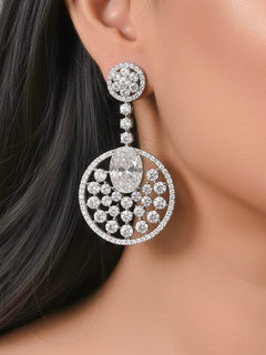 Close-up of a woman wearing an ornate Western (Silver Polish) White Diamond Earrings with American Diamond and Colored Stones. Bride wearing luxury artificial American Diamond earrings for reception night. Reception-ready look completed with statement artificial jewelry American Diamond earrings.