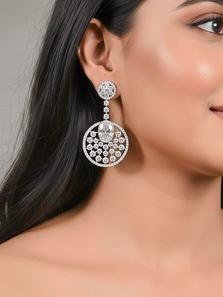 Close-up of a woman wearing an ornate Western (Silver Polish) White Diamond Earrings with American Diamond and Colored Stones. Bride wearing luxury artificial American Diamond earrings for reception night. Reception-ready look completed with statement artificial jewelry American Diamond earrings.