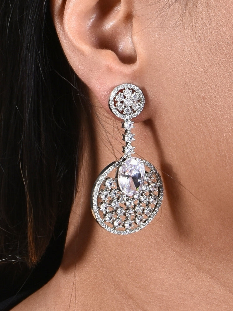 Close-up of a woman wearing an ornate Western (Silver Polish) White Diamond Earrings with American Diamond and Colored Stones. Bride wearing luxury artificial American Diamond earrings for reception night. Reception-ready look completed with statement artificial jewelry American Diamond earrings.