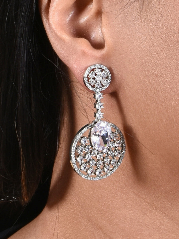 Close-up of a woman wearing an ornate Western (Silver Polish) White Diamond Earrings with American Diamond and Colored Stones. Bride wearing luxury artificial American Diamond earrings for reception night. Reception-ready look completed with statement artificial jewelry American Diamond earrings.