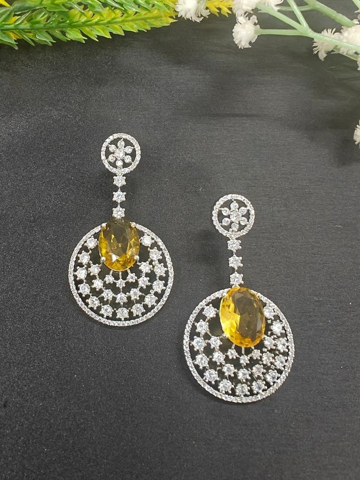 Close-up of an ornate Western (Silver Polish) Yellow Diamond Earrings with American Diamond and Colored Stones. Bride wearing luxury artificial American Diamond earrings for reception night. Reception-ready look completed with statement artificial jewelry American Diamond earrings.