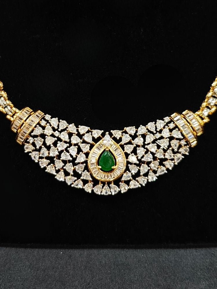 Close-up of an ornate Western (Silver Polish) Green Collar jewellery set and earrings with Green Colored Stone and American Diamond.Woman styling a statement American diamond necklace with an off-shoulder gown for a reception. Party wear outfit completed with a lightweight American diamond necklace.