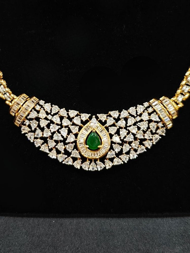 Close-up of an ornate Western (Silver Polish) Green Collar jewellery set and earrings with Green Colored Stone and American Diamond.Woman styling a statement American diamond necklace with an off-shoulder gown for a reception. Party wear outfit completed with a lightweight American diamond necklace.