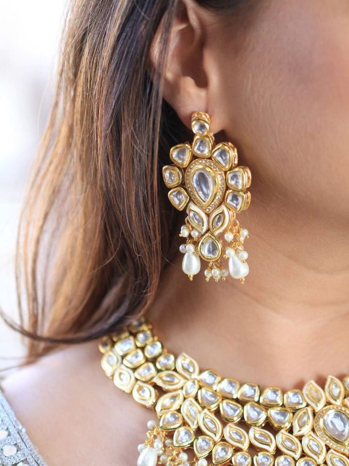 Close-up of a woman wearing an ornate traditional Gold Collar Necklace set, Eaarings and Mangtikka with Kundan, Pearls and American Diamonds. Bride wearing a traditional Kundan artificial necklace set for her wedding ceremony. Royal bridal look featuring a traditional Kundan necklace set.