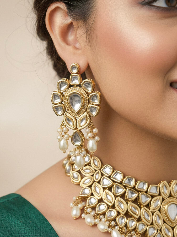 Close-up of a woman wearing an ornate traditional Gold Collar Necklace set, Eaarings and Mangtikka with Kundan, Pearls and American Diamonds. Bride wearing a traditional Kundan artificial necklace set for her wedding ceremony. Royal bridal look featuring a traditional Kundan necklace set.